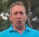 rostro de golfista mirando a cámara. Lleva camiseta azul claro. Se ven parcialmente sus hombros. Al fondo, arboleda.