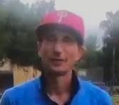 rostro de golfista mirando a cámara. Lleva gorra roja y camiseta azul. Se ven parcialmente sus hombros. Al fondo, arboleda y cielo nublado.
